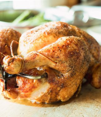 Rotisserie chicken cooked over fire. Spit-roasting self bastes the bird. The result - a succulent, crispy bird served up with a simple board sauce.