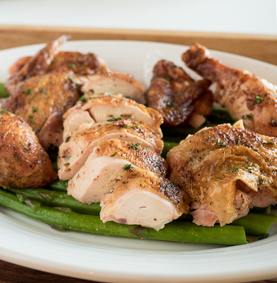 Rotisserie chicken cooked over fire. Spit-roasting self bastes the bird. The result - a succulent, crispy bird served up with a simple board sauce.