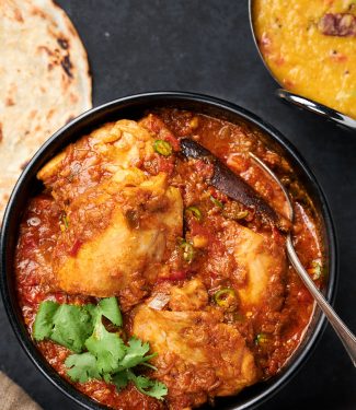 Simple chicken curry in a bowl with serving spoon from above.