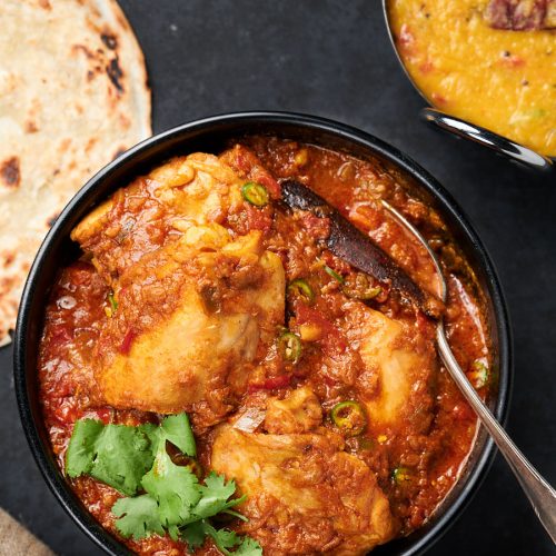 Simple chicken curry in a bowl with serving spoon from above.