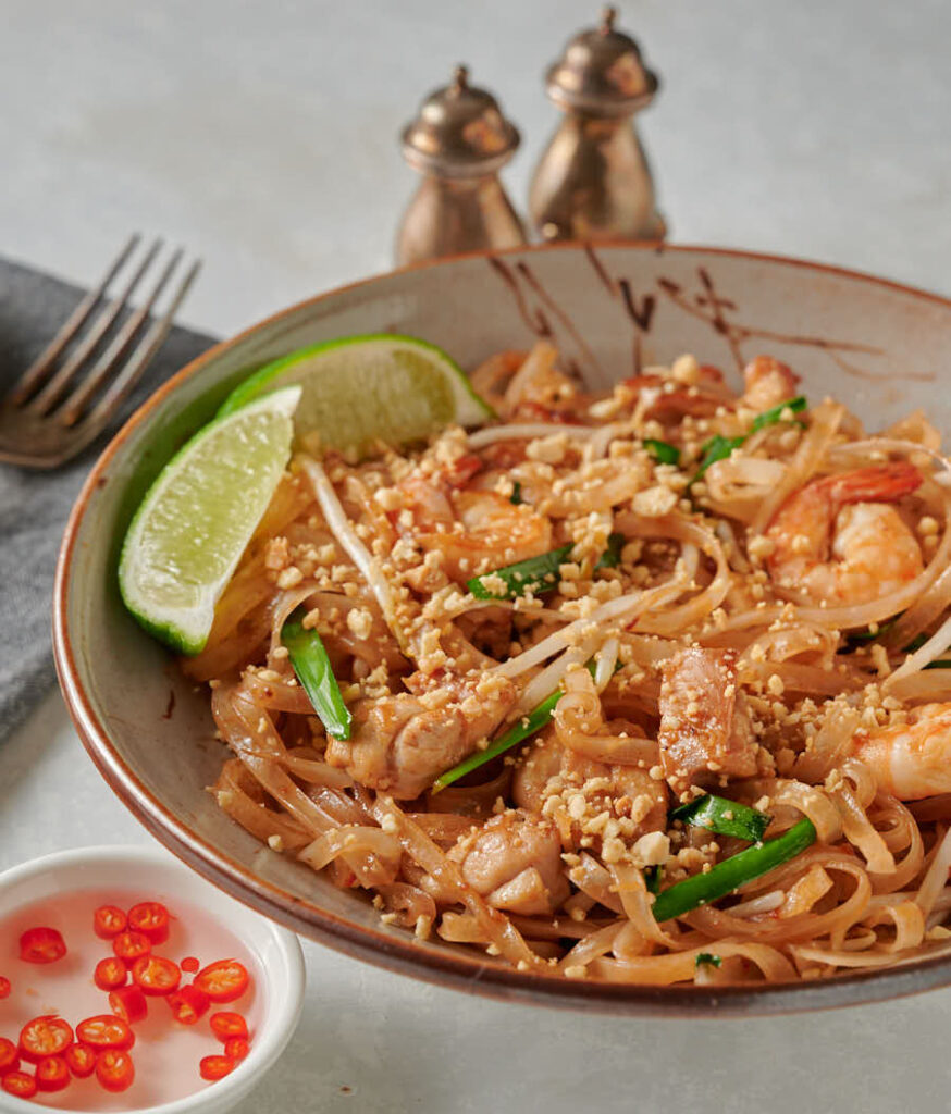 Easy pad Thai garnished with lime in a bowl. From the front.