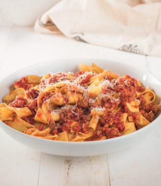 Neapolitan ragu on pappardelle in a white bowl.