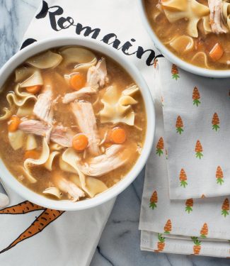 Turkey noodle soup with carrots in a white bowl.
