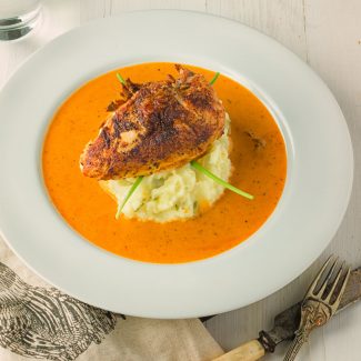 Chicken with creole cream sauce on a bed of green chili, garlic mashed potatoes.