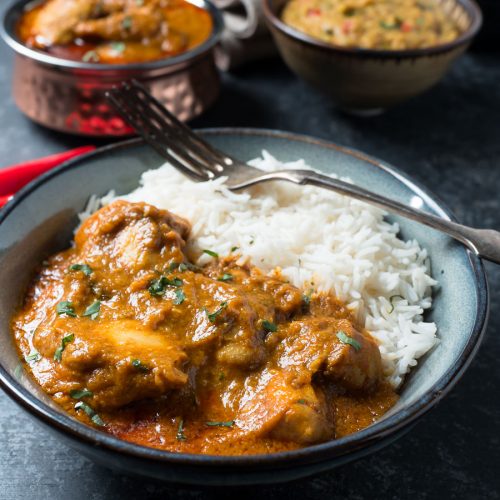 Bowl of chicken madras with rice from the front.