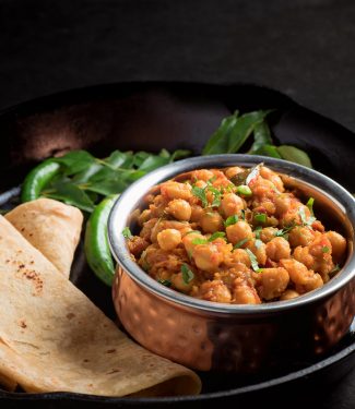 Chana masala in a copper bowl from the front.