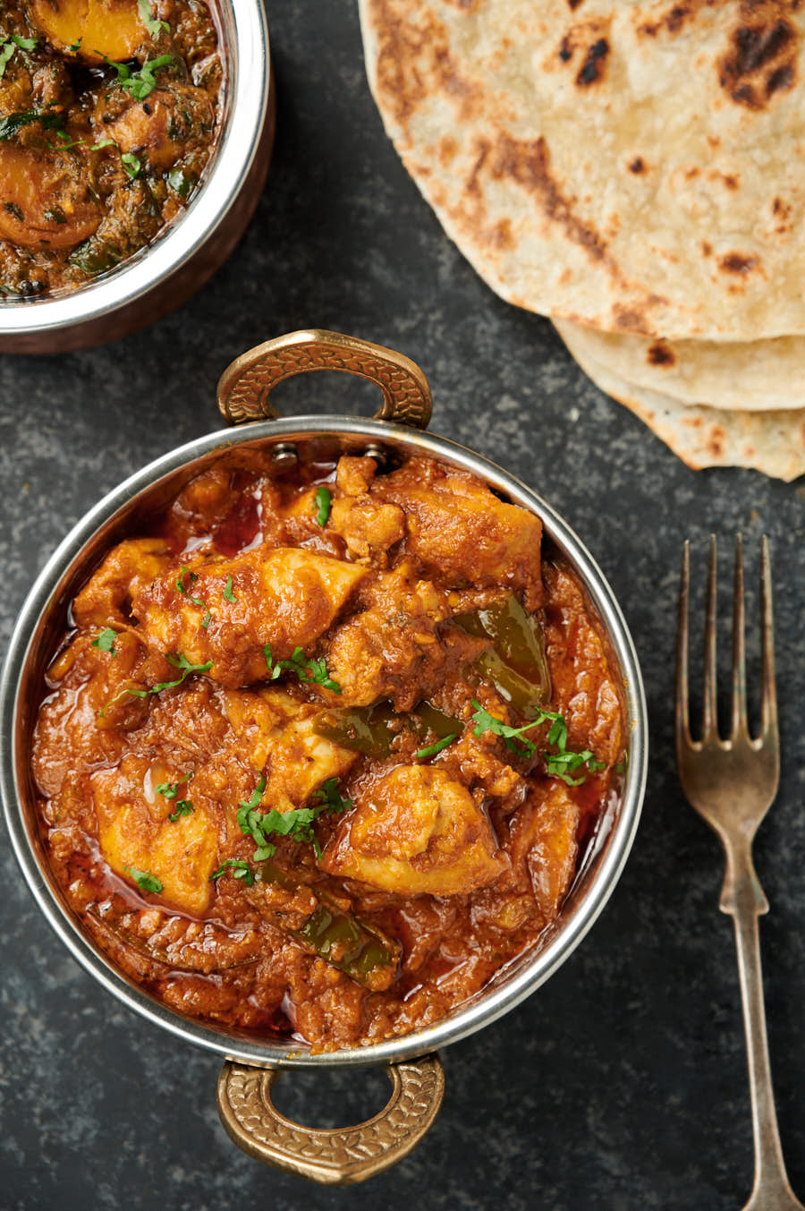 Close up of chicken dopiaza curry in a serving bowl from above.