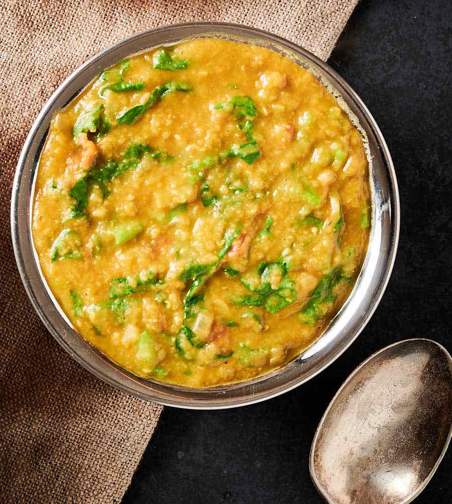 Lentil curry with spinach in a copper bowl from above.