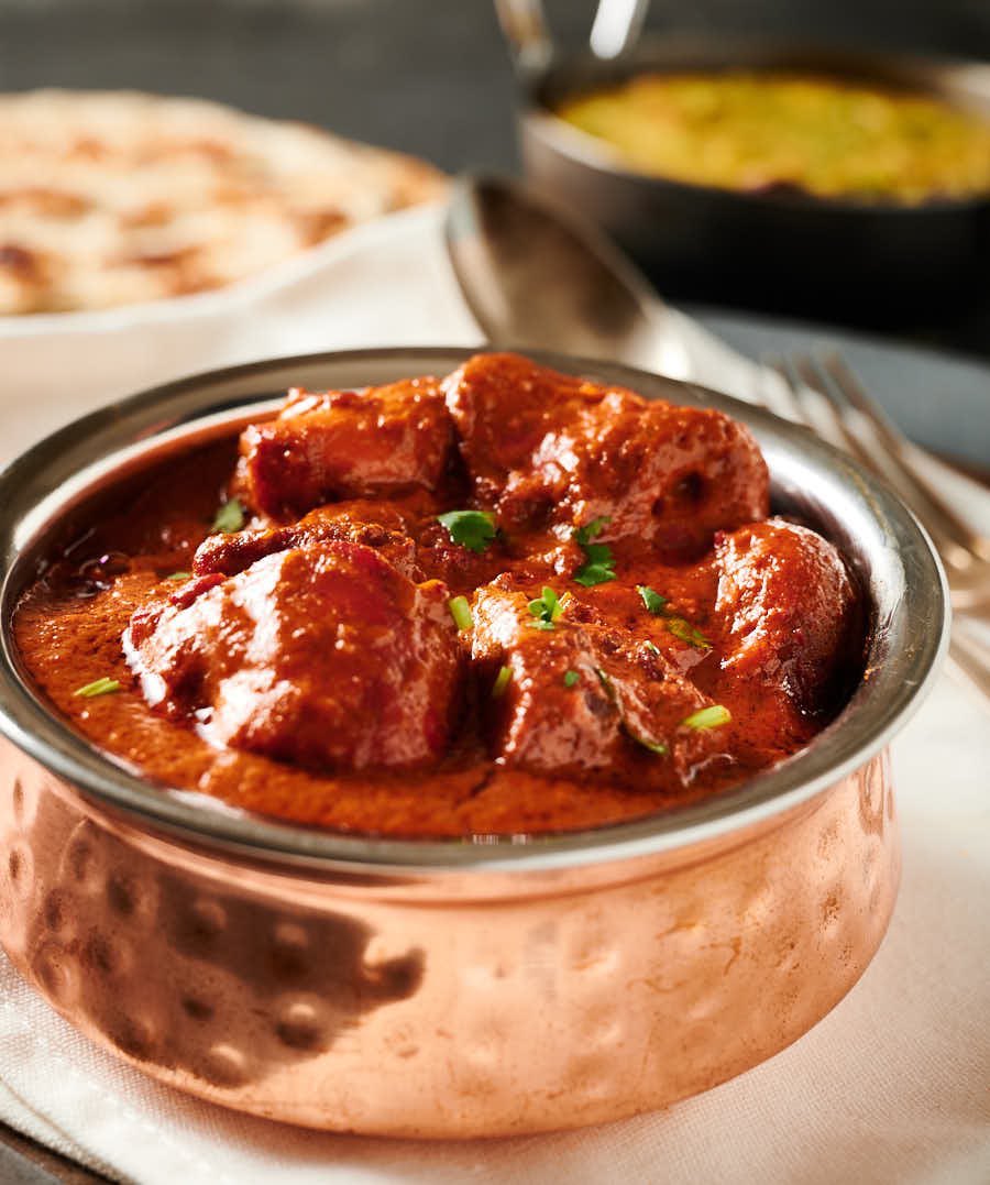 Chicken tikka masala in an Indian copper bowl from the front.