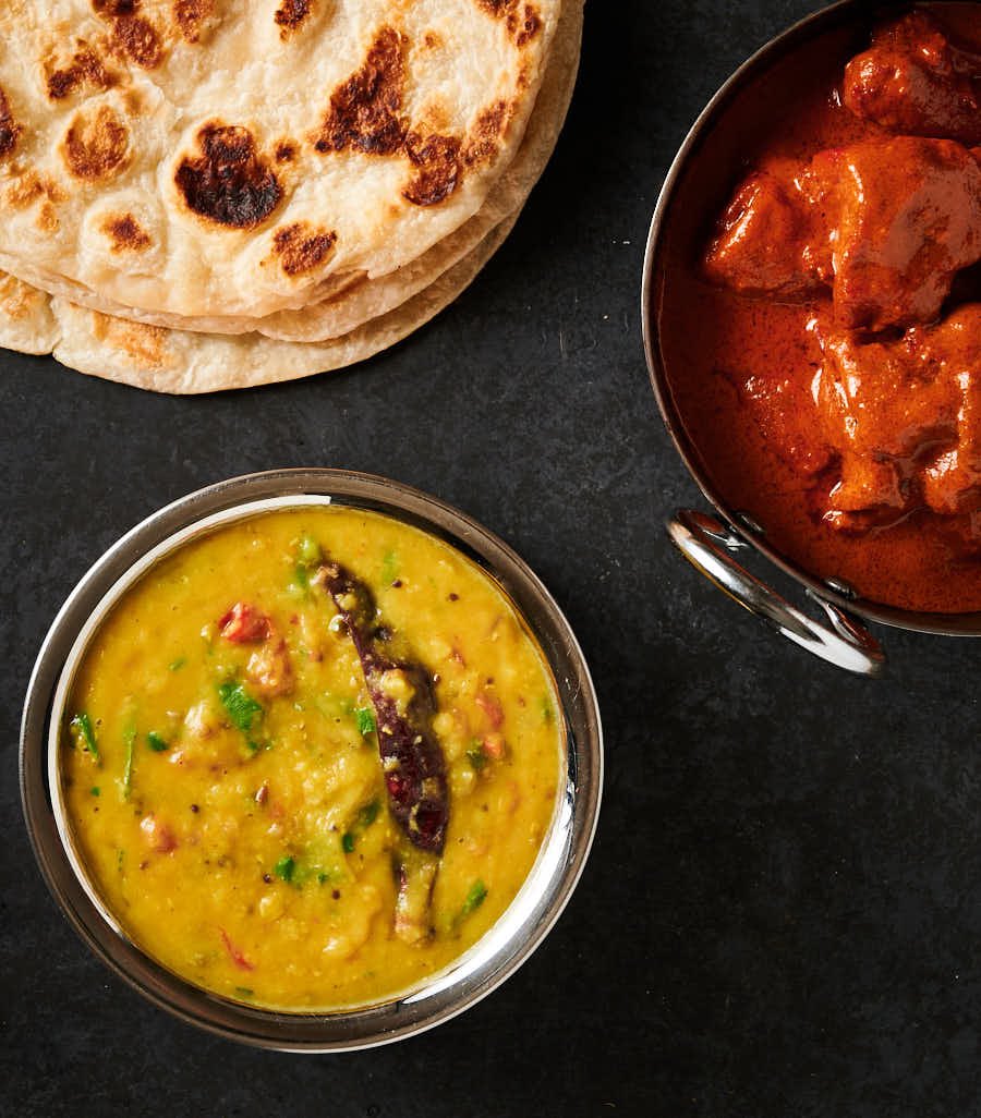 Tarka dal table scene with parathas and chicken tikka masala from above.