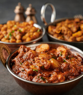 Aloo chicken curry in an Indian copper bowl from the front.