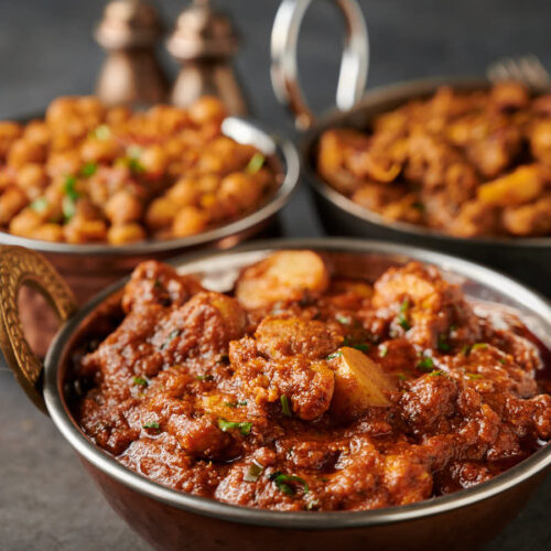 Aloo chicken curry in an Indian copper bowl from the front.