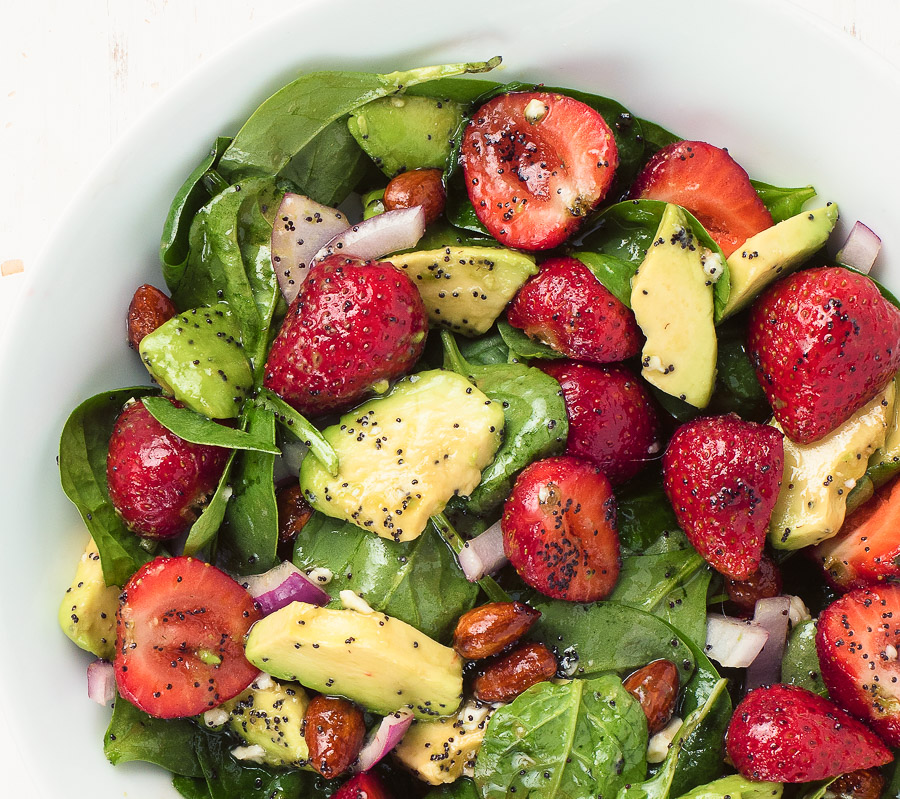 Spinach and strawberry salad in a white bowl up close.