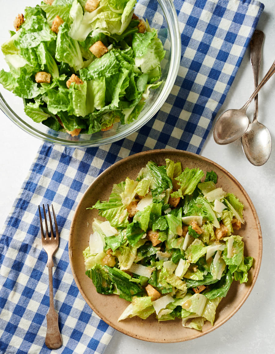 Caesar salad on plate and in salad bowl from above.