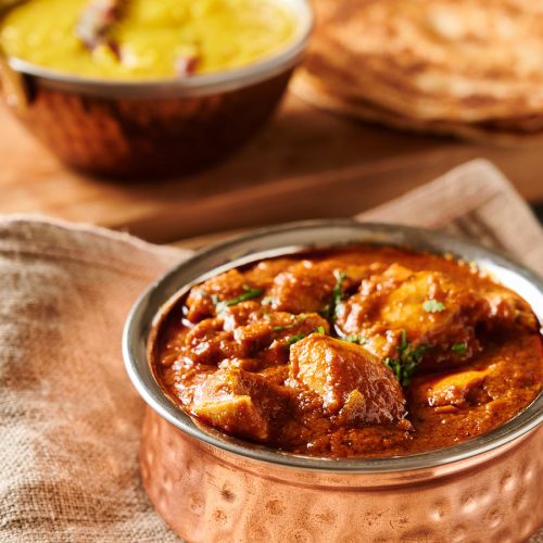 Restaurant style pathia curry in a copper bowl from the front.