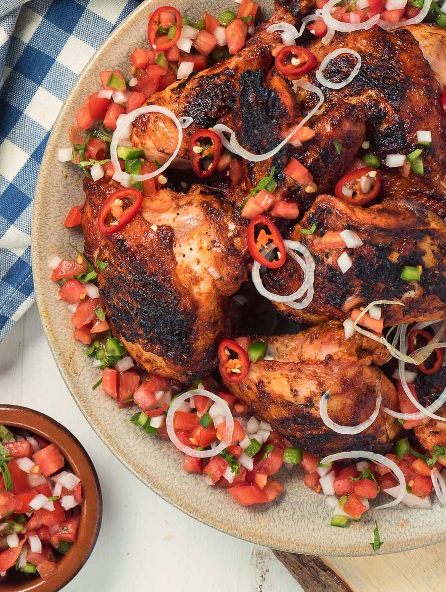 Yucatan grilled chicken on a plate with pico garnish.