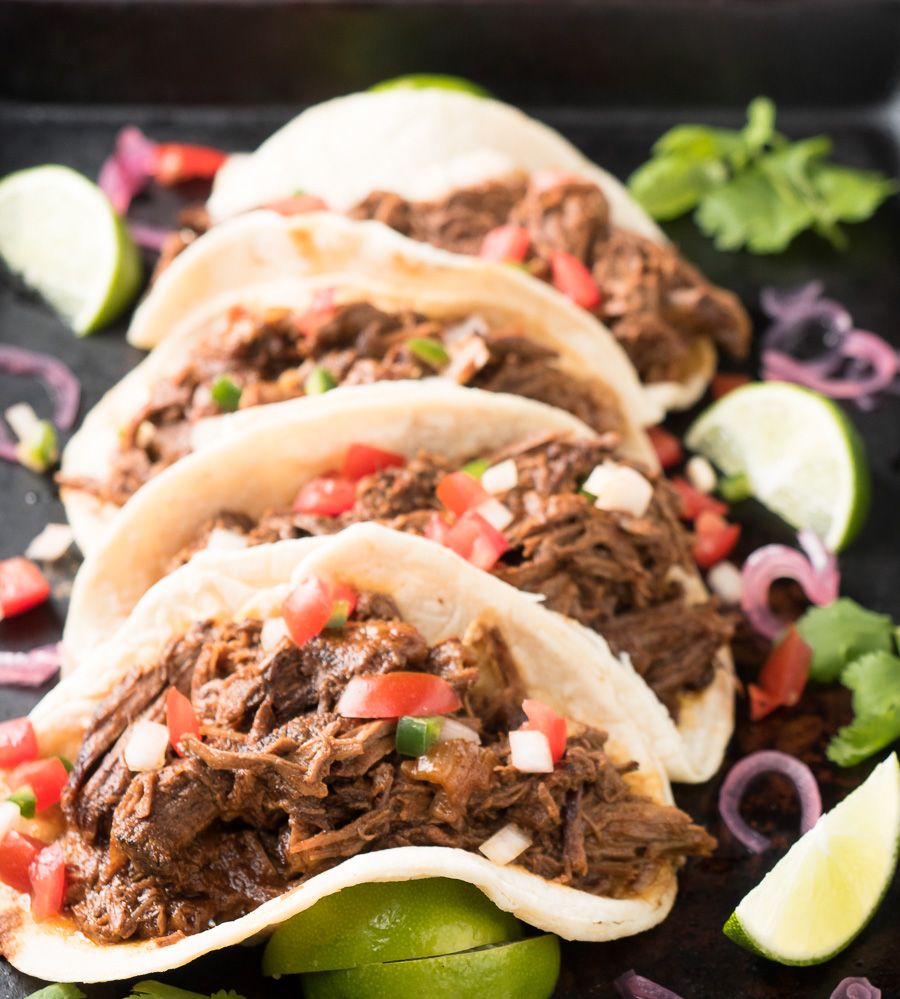 Row of beef barbacoa tacos from the front.