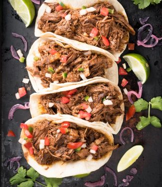Row of beef barbacoa tacos with pico di gallo from above.