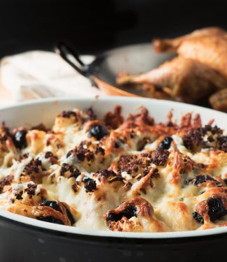 Roasted cauliflower gratin with browned melted cheese and olives front view.