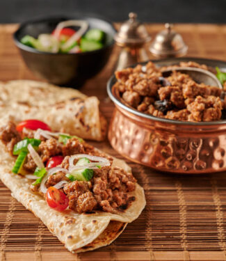 Keema on a paratha with tomato cucumber salad garnish from the front.