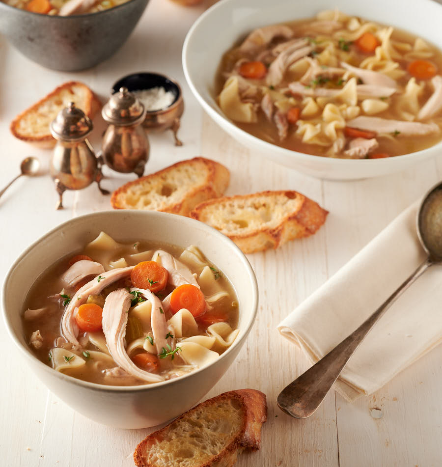 Bowl of homemade chicken noodle soup with bread.