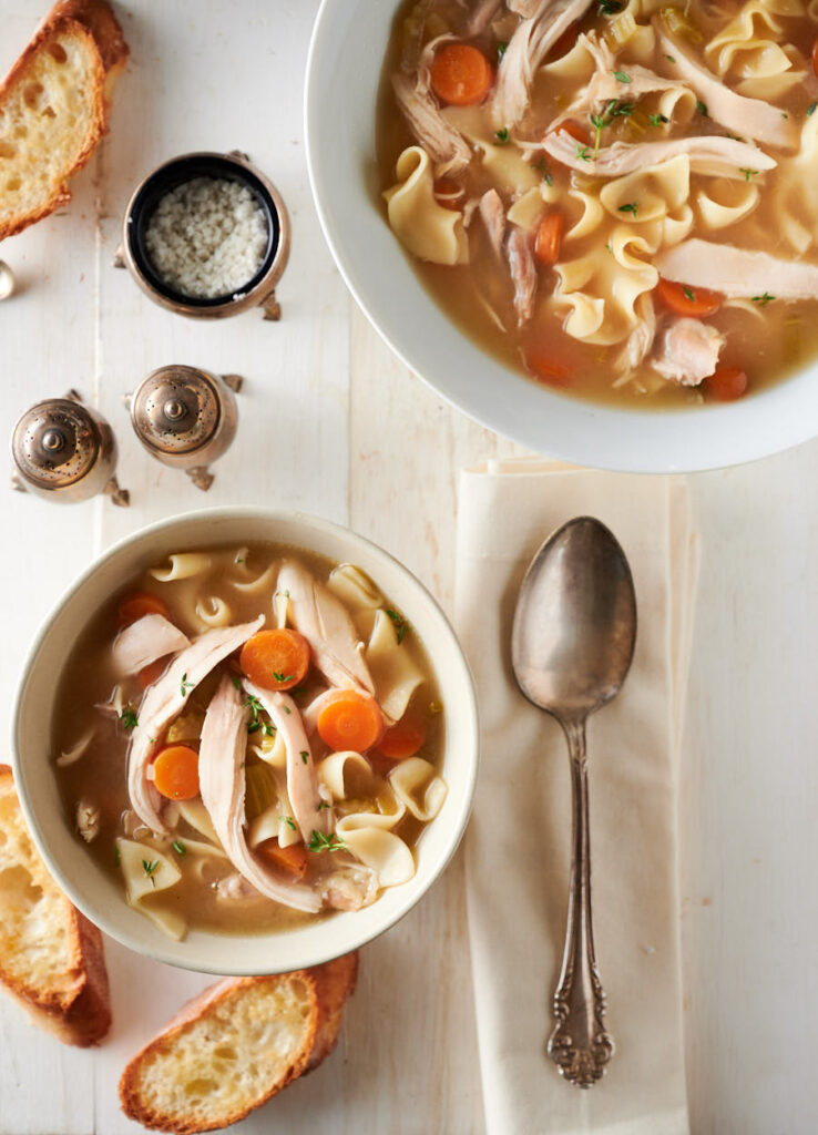 Bowl of chicken noodle soup with spoon from above.