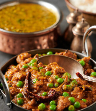 Keema matar in a carbon steel bowl with spoon closeup from the front.