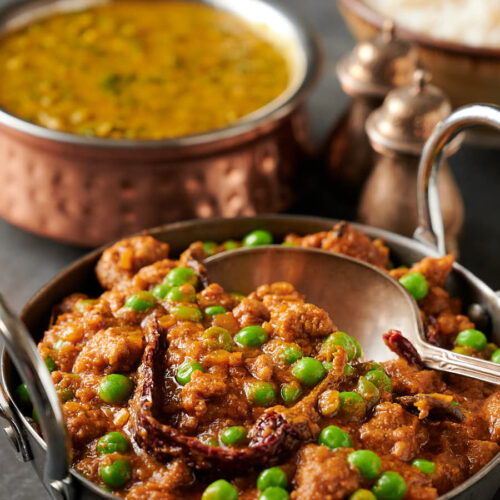 Keema matar in a carbon steel bowl with spoon closeup from the front.