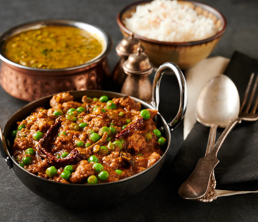 Keema matar table scene with dal palak and rice from the front.