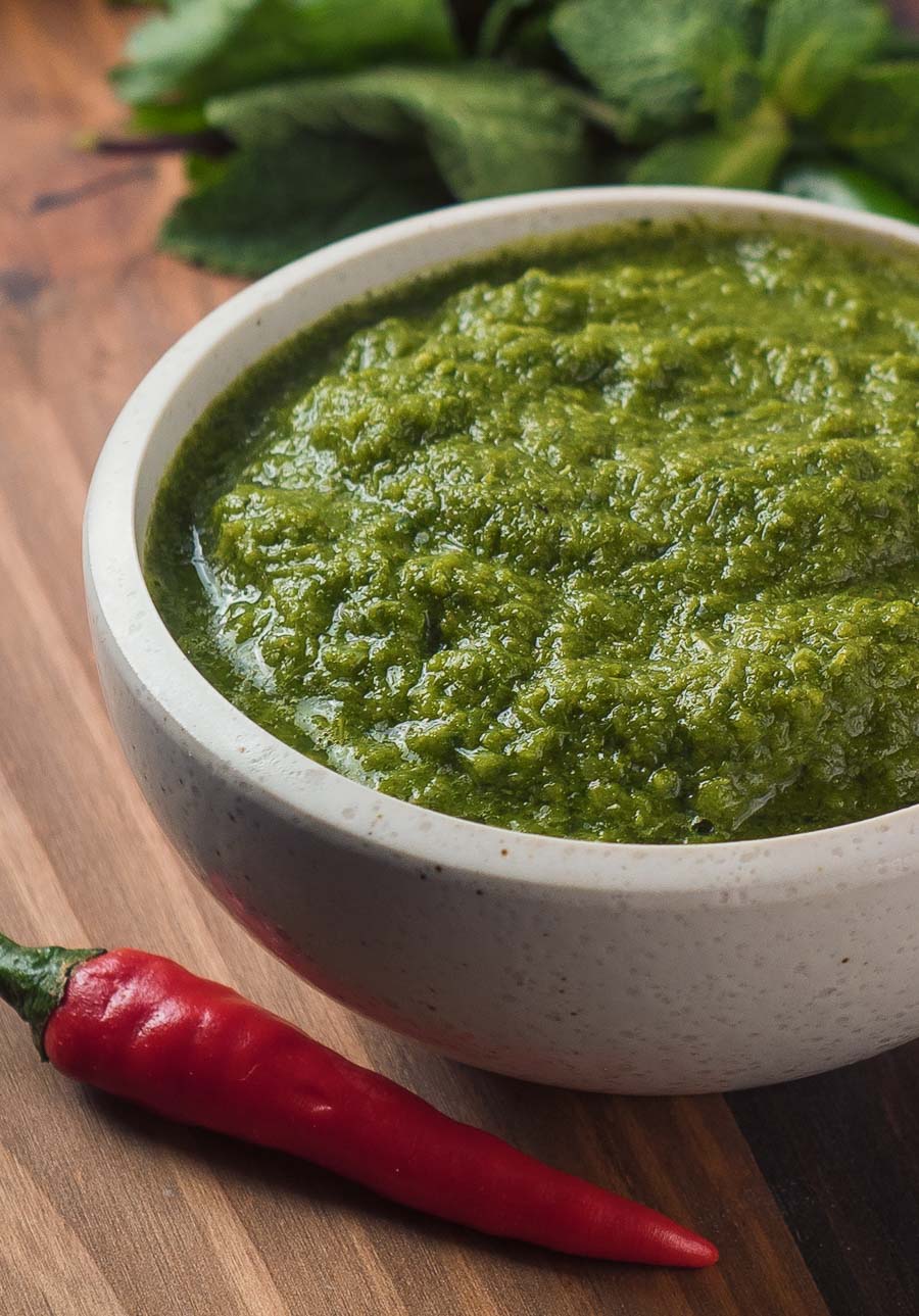 Close up of mint coriander chutney in a white bowl.