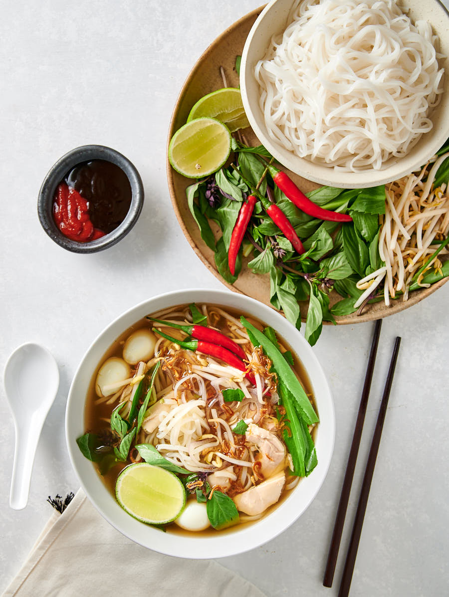 Bowl of pho ga and plate of garnishes from the top.