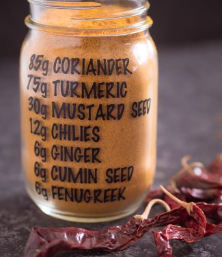 Homemade curry powder in a mason jar with the recipe on the jar.