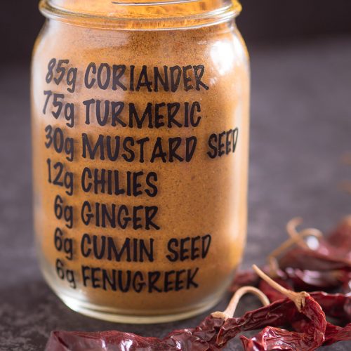 Homemade curry powder in a mason jar with the recipe on the jar.