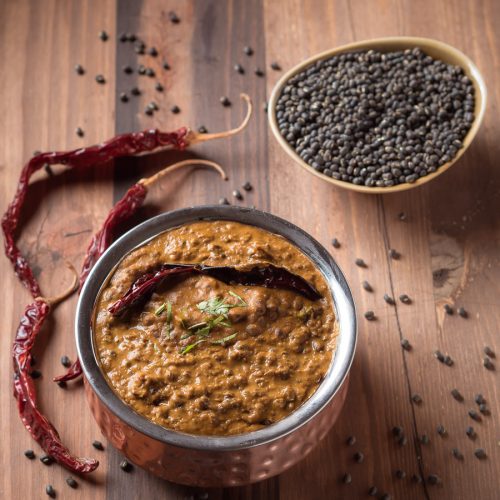 Punjabi dal makhani in a small copper pot garnished with a red chili.