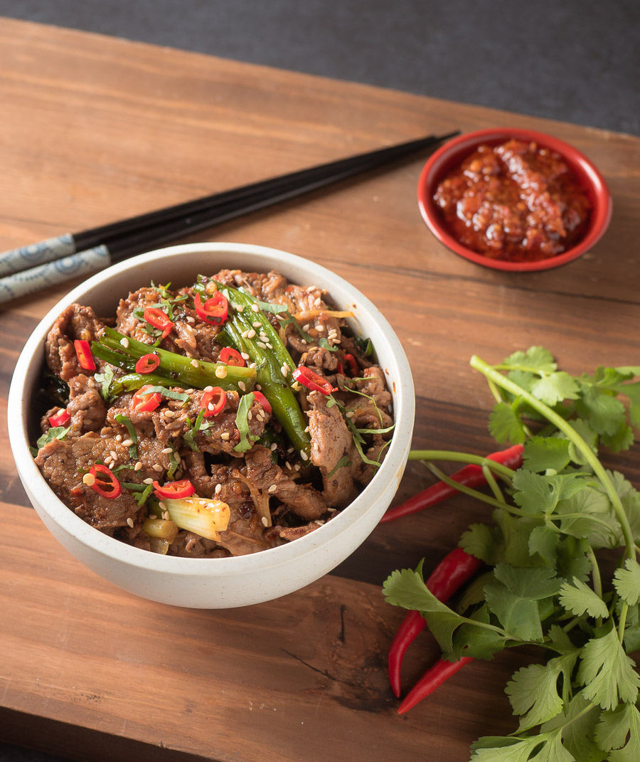 ginger beef stir fry in a white bowl with garnish