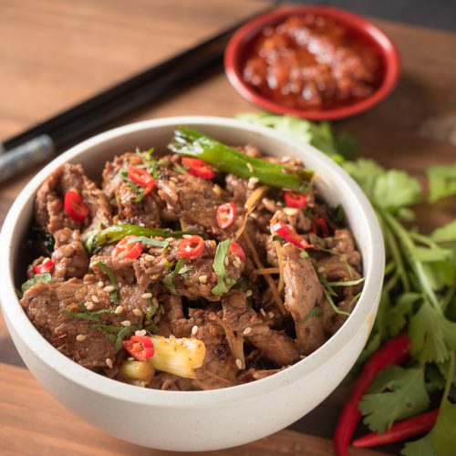 ginger beef stir fry in a white bowl close up