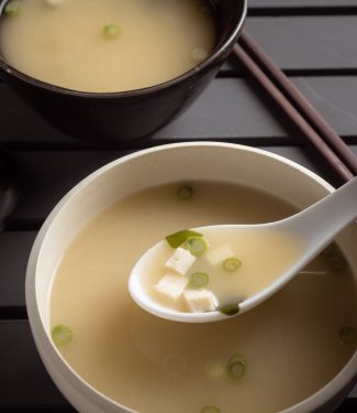 Japanese miso soup in a white bowl with spoon.