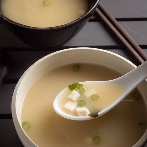 Japanese miso soup in a white bowl with spoon.