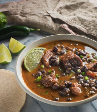 Mexican pork and black bean stew garnished with lime slices