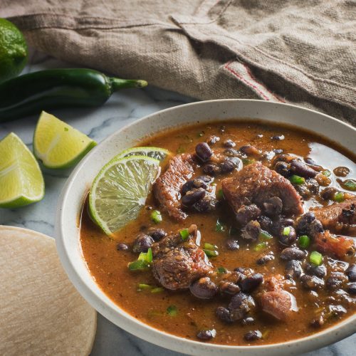 Mexican pork and black bean stew garnished with lime slices