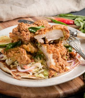 Crispy Kerala fried chicken cut with knife and fork.