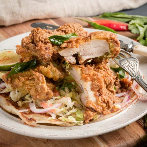 Crispy Kerala fried chicken cut with knife and fork.