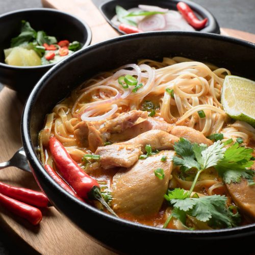 Chicken Khao soi in a black bowl from the front.