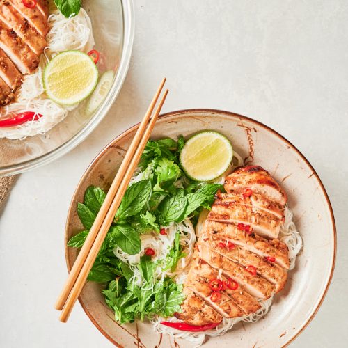 Closeup of Vietnamese lemongrass chicken in a bowl with chopsticks from above.