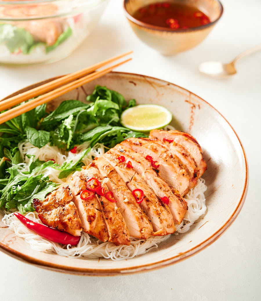 Closeup of Vietnamese lemongrass chicken in a bowl with chopsticks from the front.