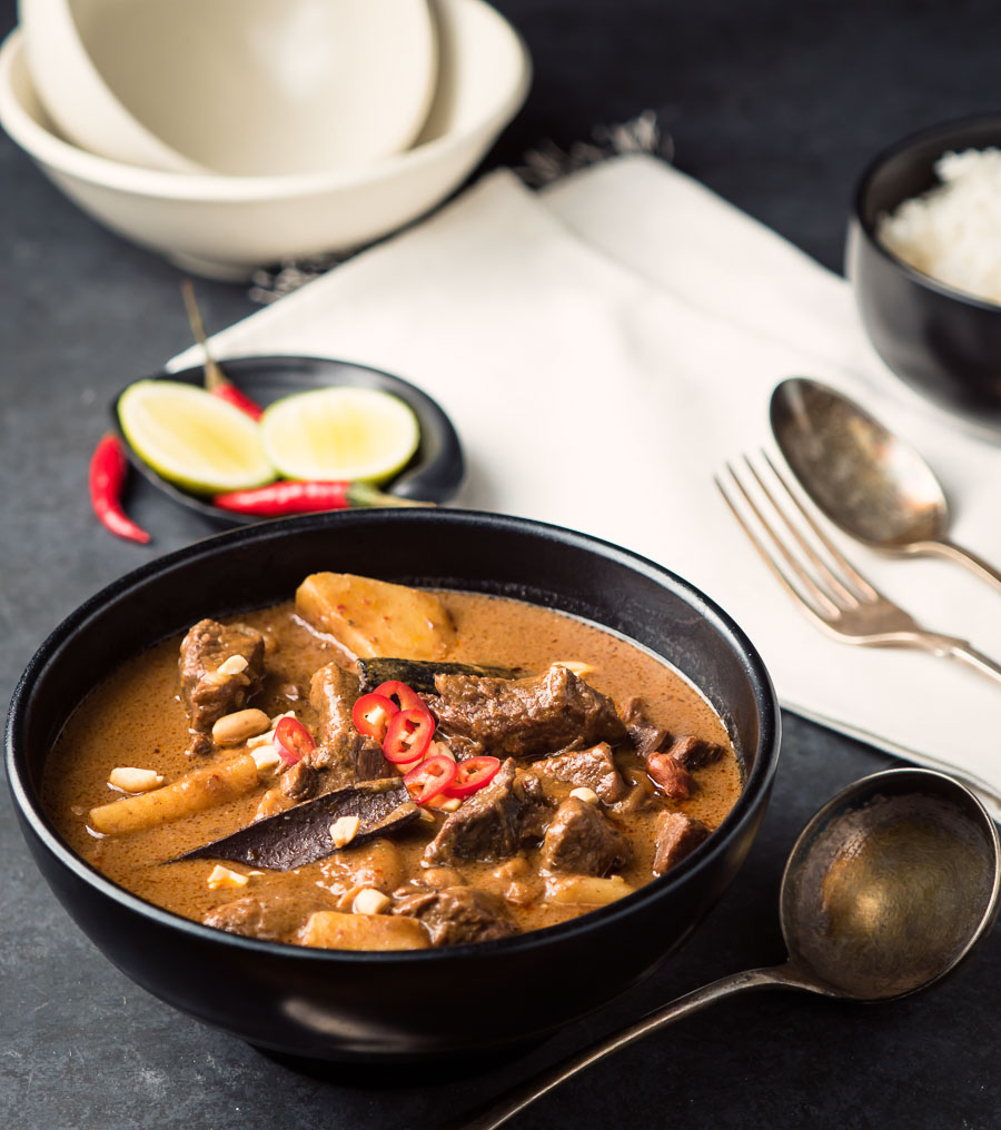 Beef massaman curry in a black bowl.