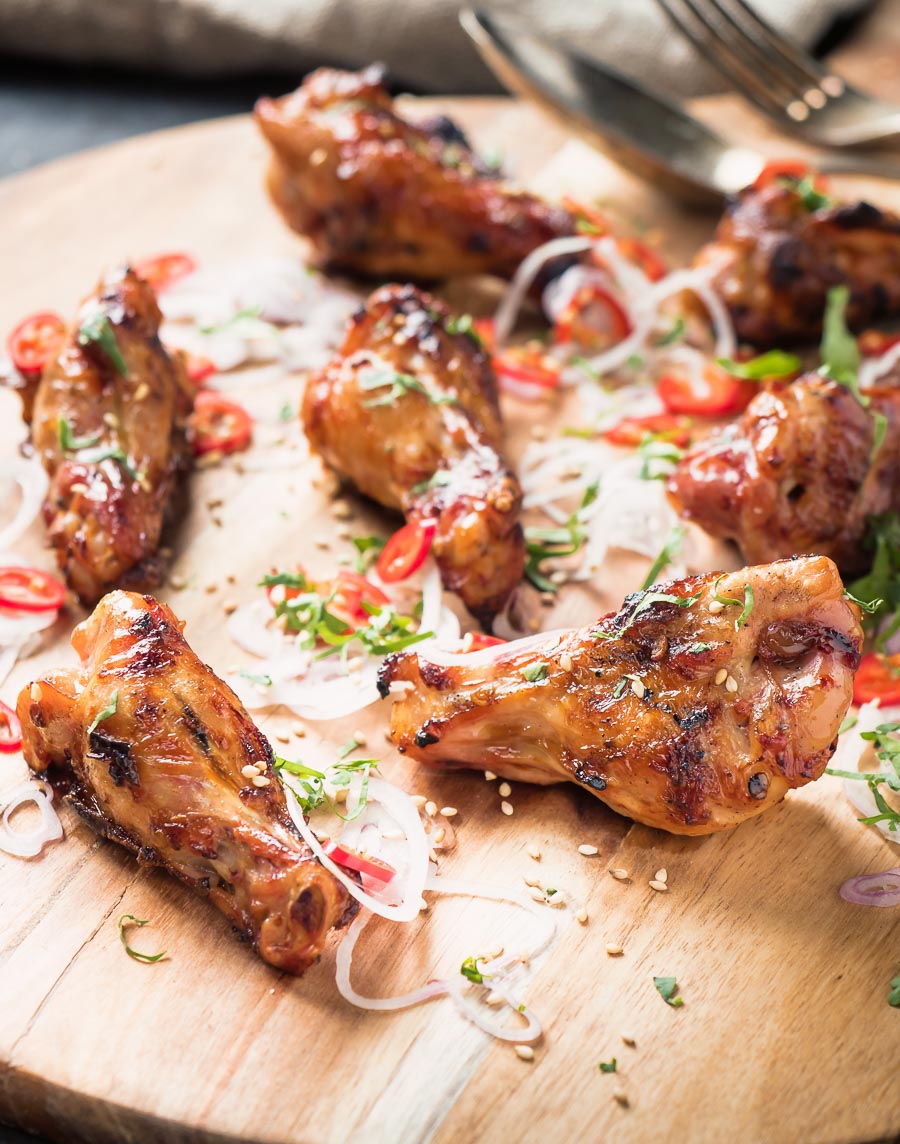 Asian grilled chicken wings on a cutting board from the front.