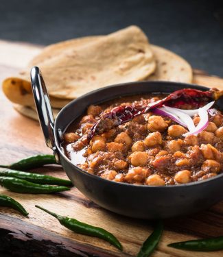 Punjabi chole masala in an Indian iron dish from the front.