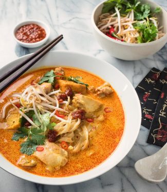 Laksa coconut curry soup in a white bowl from the front.