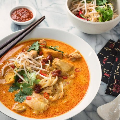 Laksa coconut curry soup in a white bowl from the front.